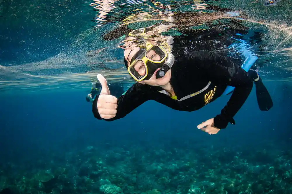 A diver giving a thumbs up just beneath the surface