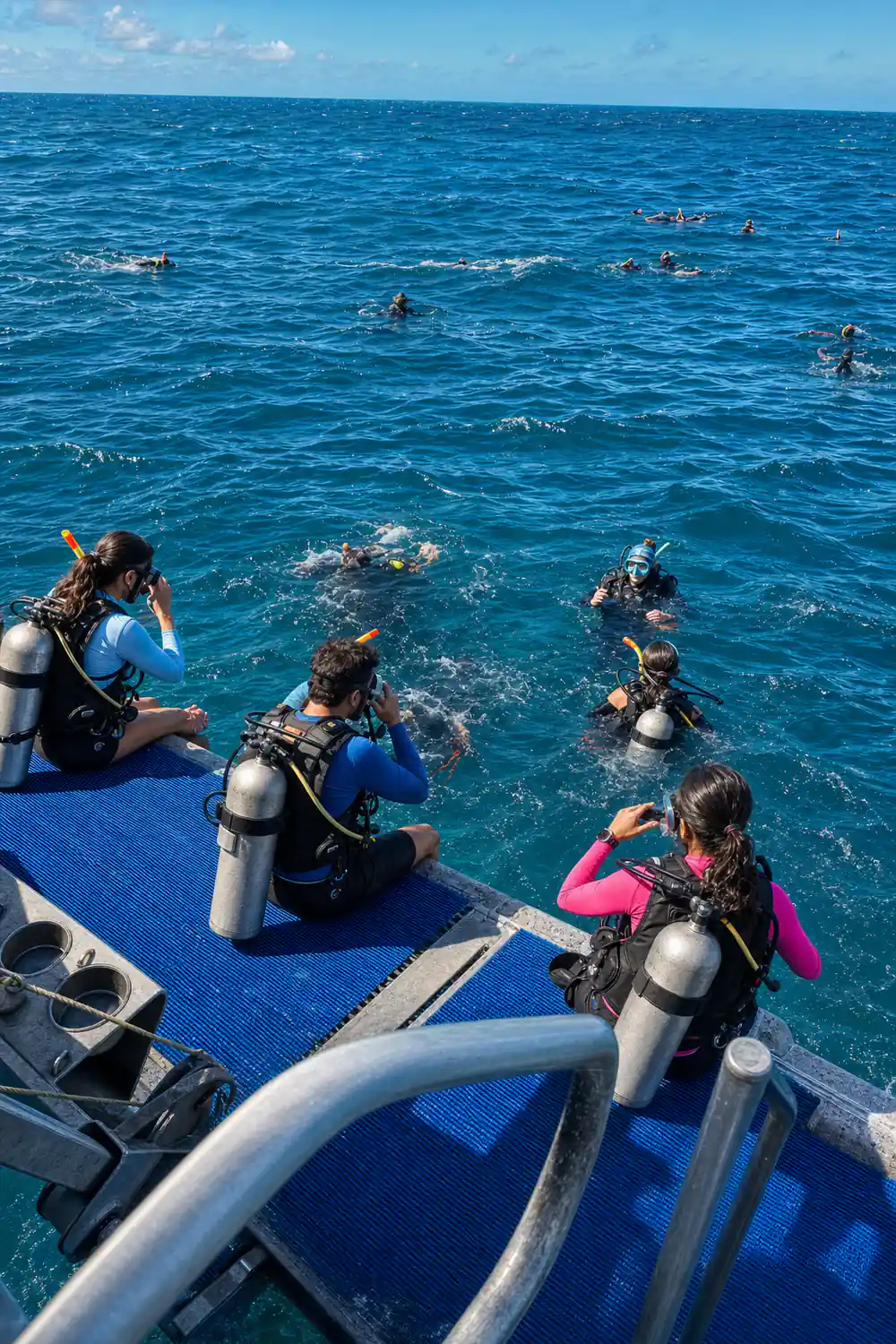 Divers entering the water in sequence from the blue platform