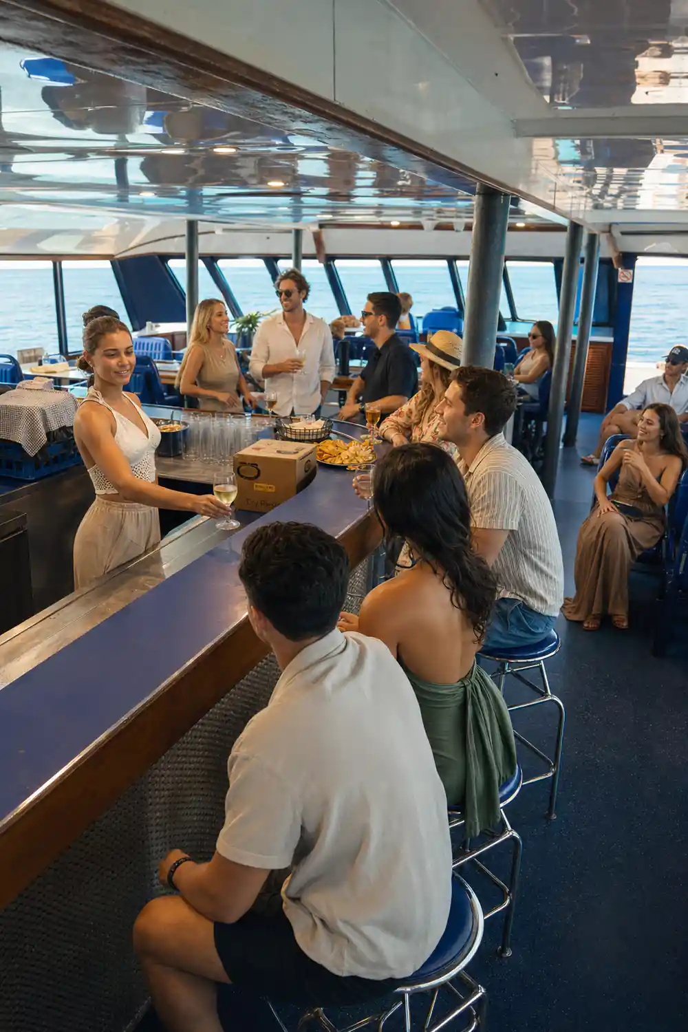 Guests standing at the boat's timber bar with glasses